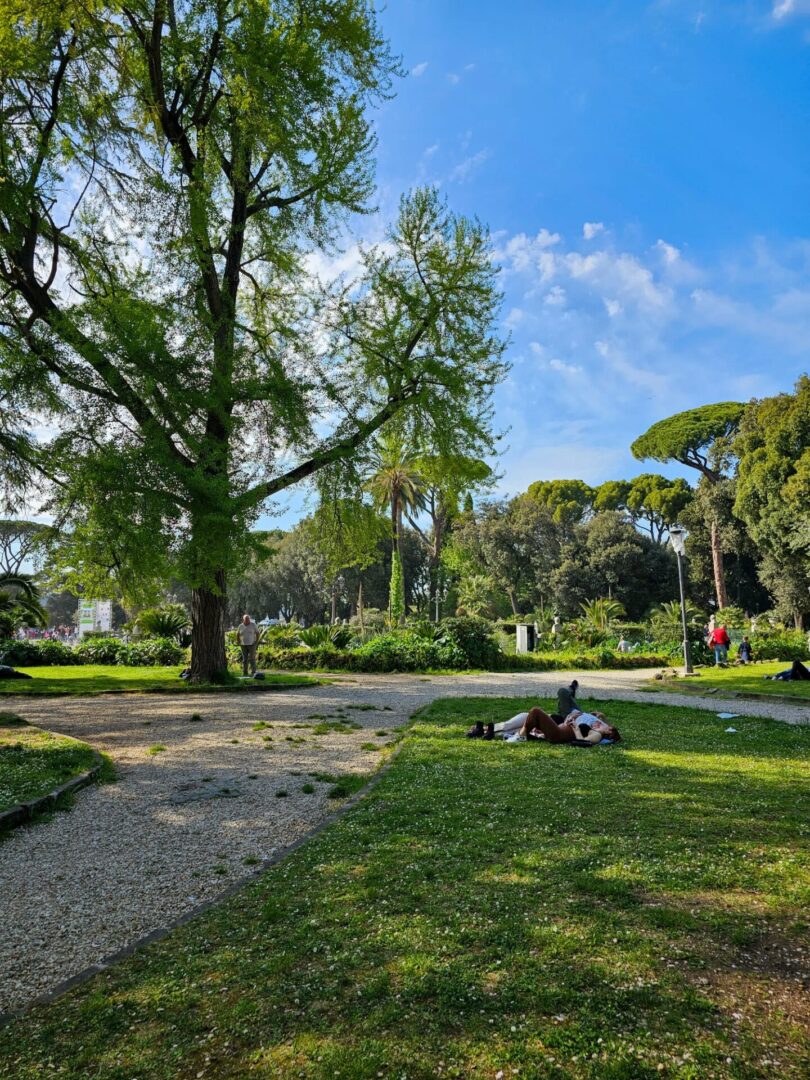 Jardins da Villa Borghese ao fim do dia, com pessoas a conversar e descansar na relva