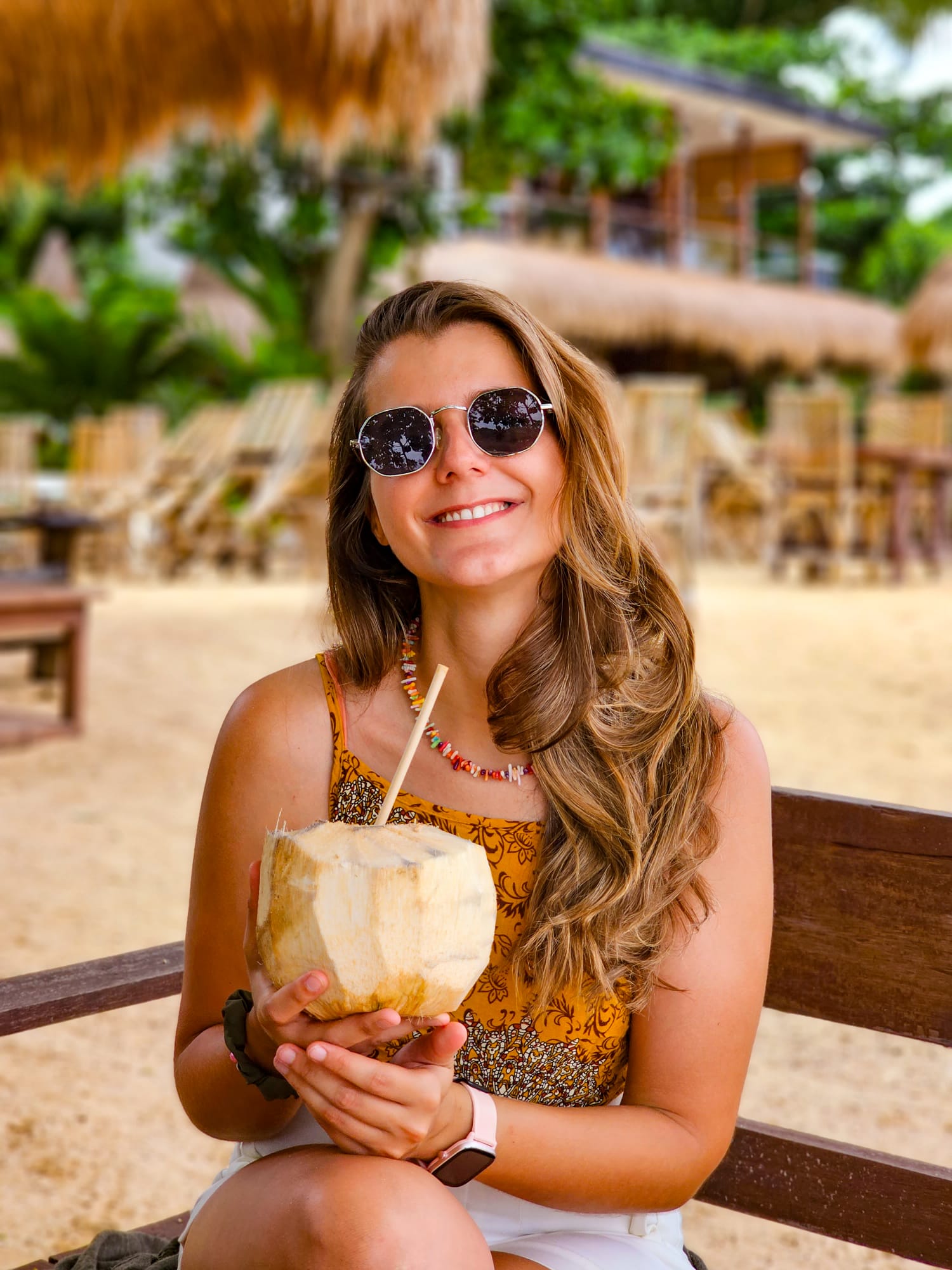 Rapariga feliz a beber uma água de coco em El Nido